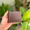 Handmade full grain brown pull up leather bifold wallet with same color saddle stitching and embossed logo