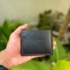 Smooth black full grain leather back of bifold wallet showing hand-burnished edges and red stitching detail