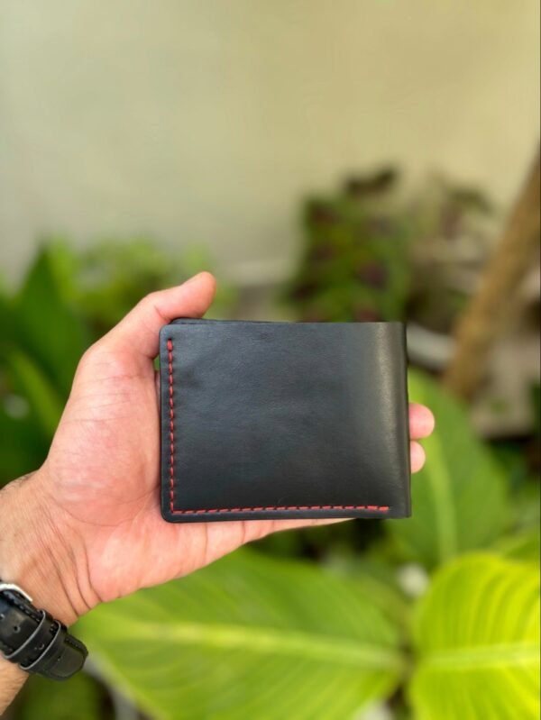 Smooth black full grain leather back of bifold wallet showing hand-burnished edges and red stitching detail